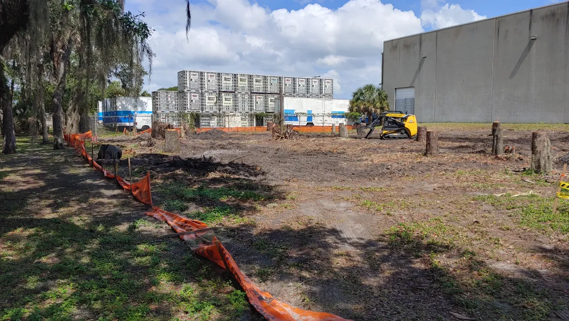 Commercial land clearing project by Five Star Tree Service in Bradenton, FL showing cleared construction site with yellow skid steer equipment and safety fencing